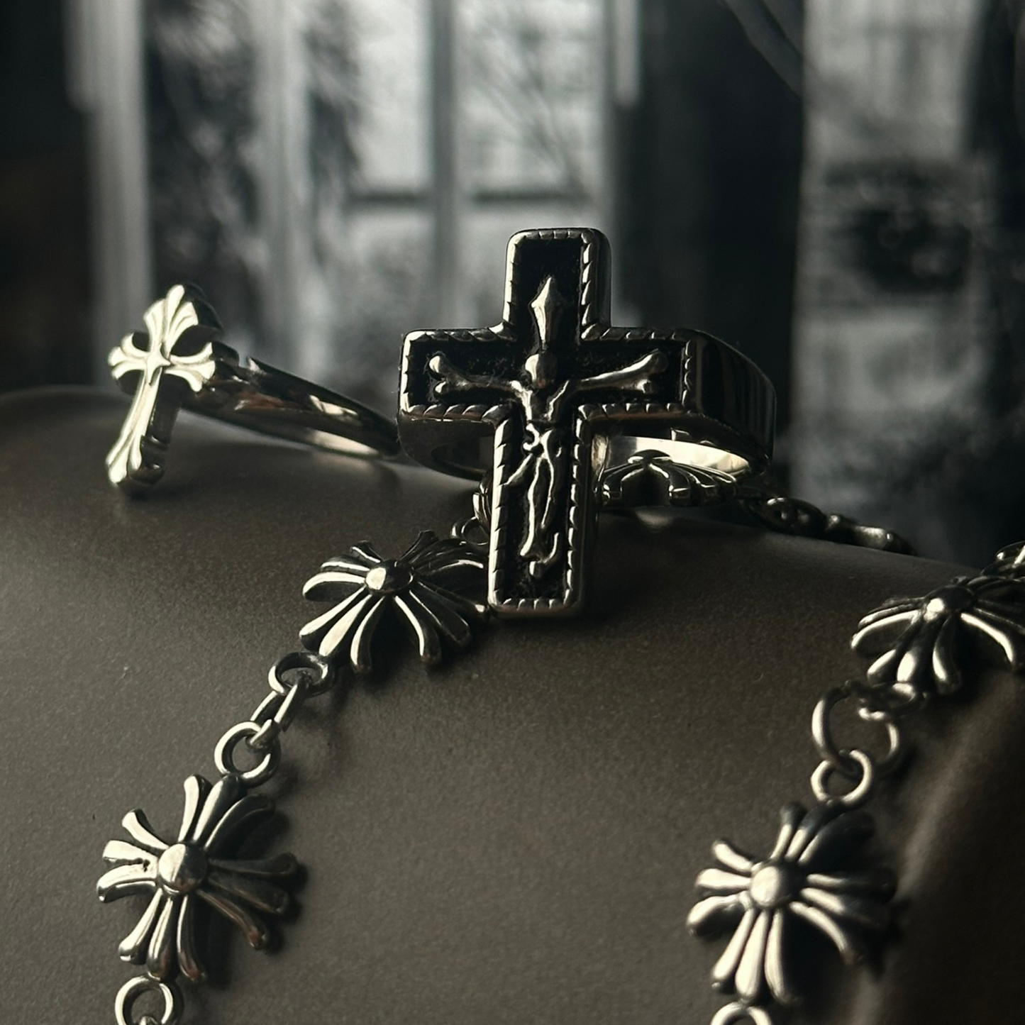 Anillo de acero inoxidable 'Follow Ring Lil Cross', acompañado por el 'Follow Ring Big Cross' y la pulsera 'Follow Bracelet', de la marca Follow God, sobre una superficie oscura