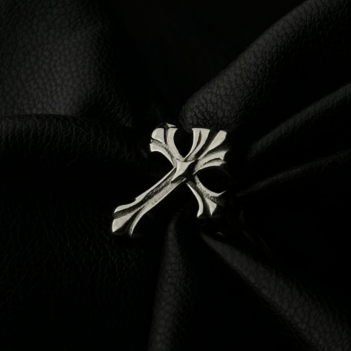 Anillo de acero inoxidable 'Follow Ring Lil Cross' con diseño de cruz en relieve, de la marca Follow God, exhibido sobre tela negra texturizada