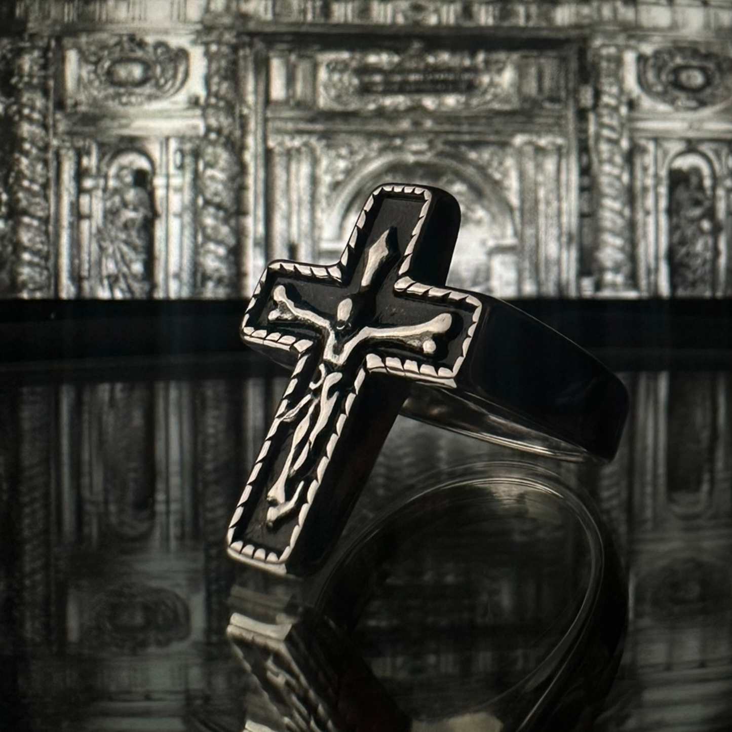 Anillo de acero inoxidable tipo sello 'Follow Ring Big Cross' con diseño de cruz en relieve, de la marca Follow God, con fondo detallado de arquitectura clásica